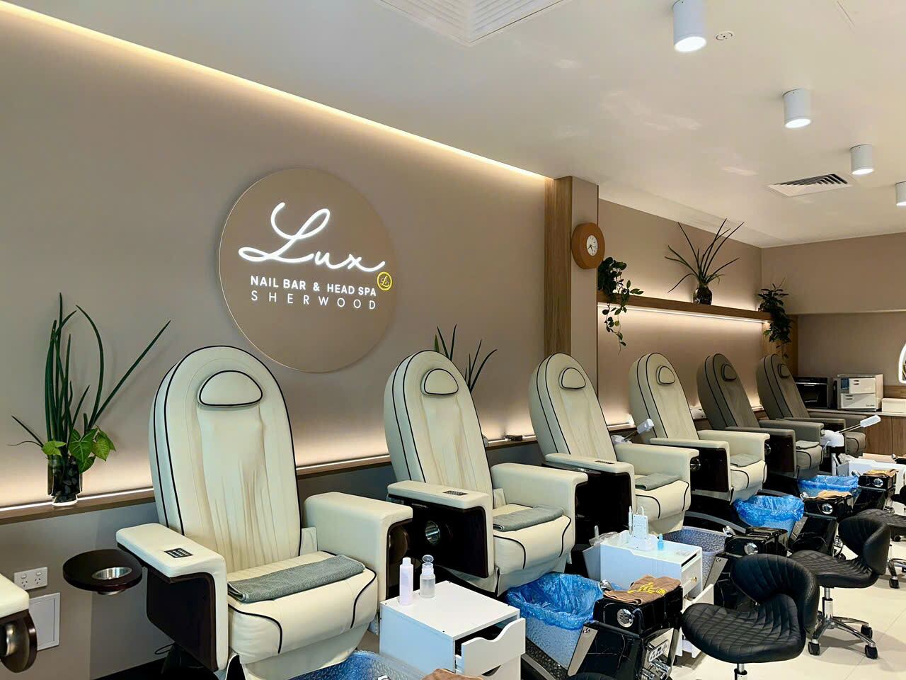 Cream pedicure chairs beneath the illuminated Lux Nail Bar & Head Spa Sherwood sign