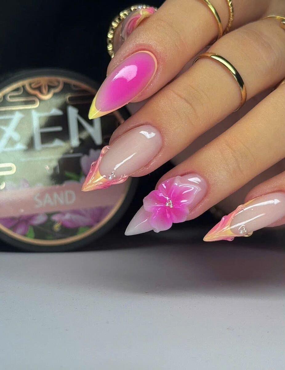 Pink stiletto acrylic nails with a painted flower and gold rings